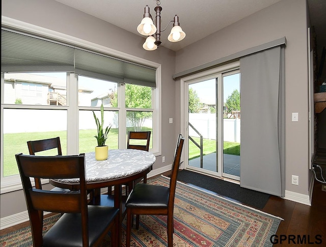 dining space featuring a chandelier, baseboards, and dark wood-type flooring