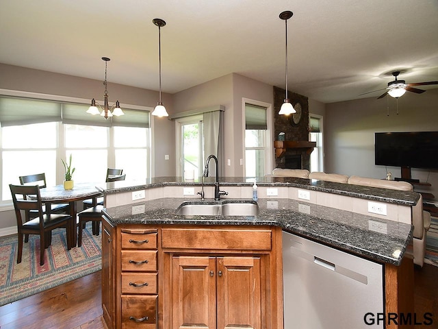 kitchen featuring stainless steel dishwasher, a sink, open floor plan, brown cabinets, and a ceiling fan
