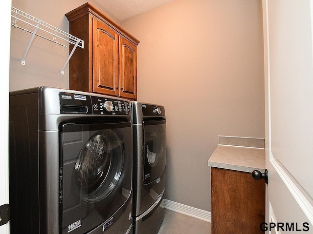 washroom with cabinet space, washing machine and clothes dryer, baseboards, and tile patterned flooring