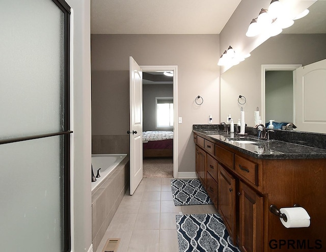 bathroom with tile patterned floors, double vanity, baseboards, tiled bath, and ensuite bathroom