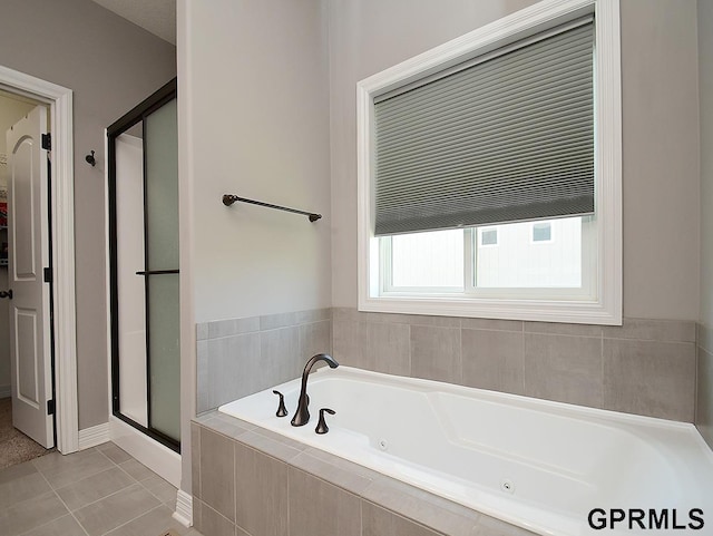 bathroom with a stall shower, a jetted tub, tile patterned floors, and baseboards