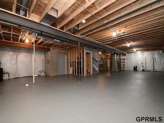 unfinished basement with heating unit and stairs