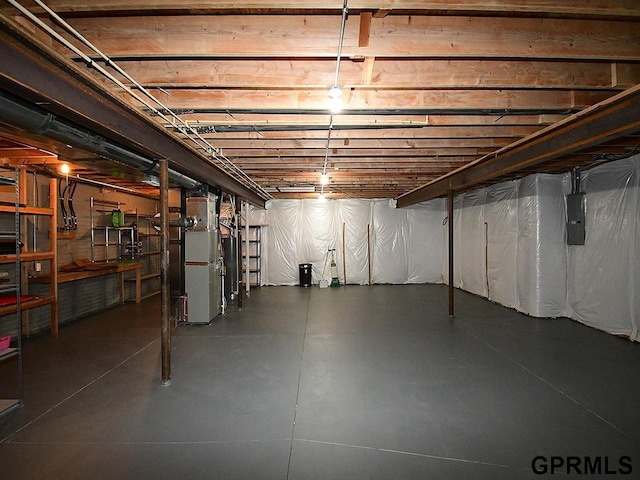unfinished basement with electric panel, water heater, and heating unit
