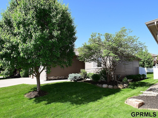 view of grassy yard with concrete driveway