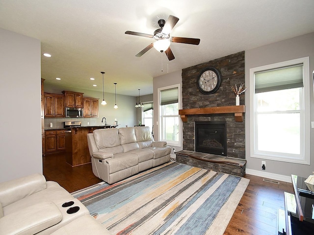 living area with dark wood-style floors, a ceiling fan, a fireplace, recessed lighting, and baseboards