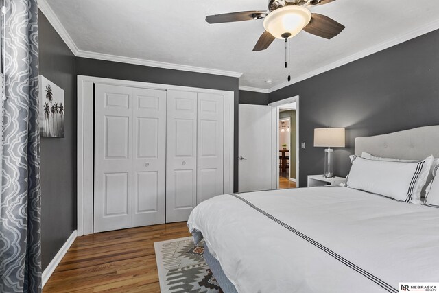 bedroom with wood finished floors, a closet, baseboards, ornamental molding, and a ceiling fan