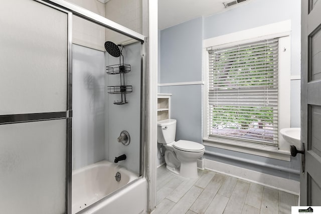 3218 Holdrege St, Lincoln, NE 68503 - full bath featuring toilet, bath / shower combo with glass door, baseboards, and wood finished floors