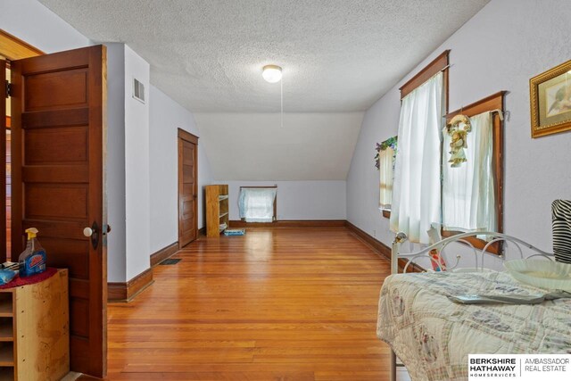 6301 SW 34th Ct, Lincoln, NE 68523 - bedroom featuring a textured ceiling, visible vents, vaulted ceiling, baseboards, and light wood-style floors