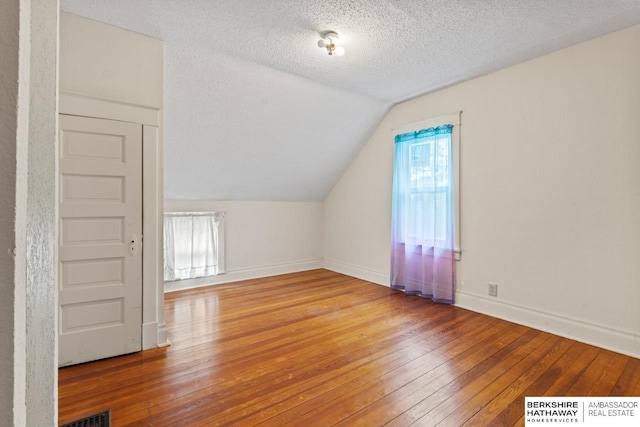 6301 SW 34th Ct, Lincoln, NE 68523 - additional living space featuring visible vents, baseboards, a textured ceiling, hardwood / wood-style flooring, and vaulted ceiling