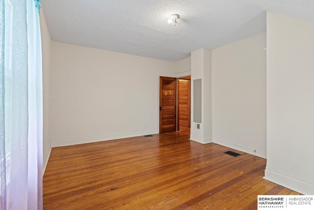 6301 SW 34th Ct, Lincoln, NE 68523 - unfurnished room featuring visible vents, a textured ceiling, baseboards, and hardwood / wood-style flooring