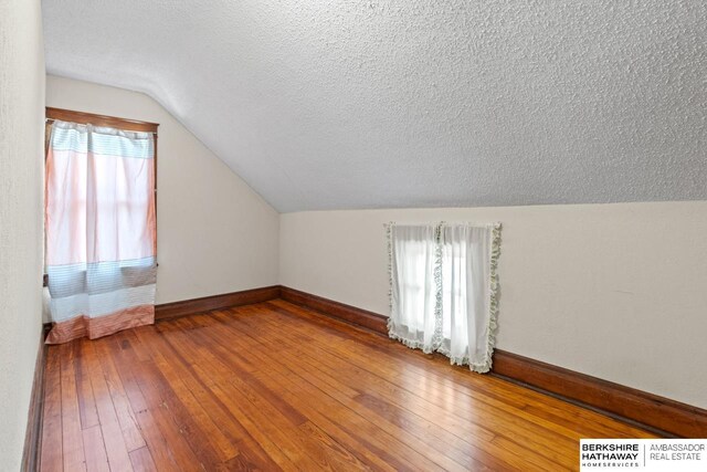 6301 SW 34th Ct, Lincoln, NE 68523 - bonus room featuring baseboards, hardwood / wood-style flooring, a textured ceiling, and lofted ceiling