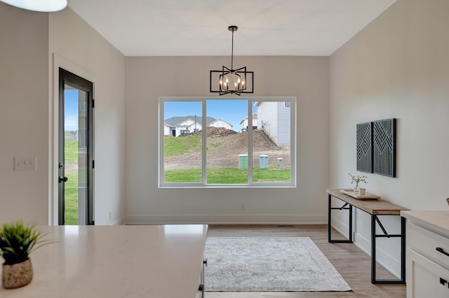 dining room featuring baseboards, an inviting chandelier, and light wood-style floors