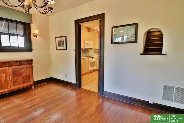 5506 Howard St, Omaha, NE 68106 - empty room featuring a chandelier, wood-type flooring, and baseboards