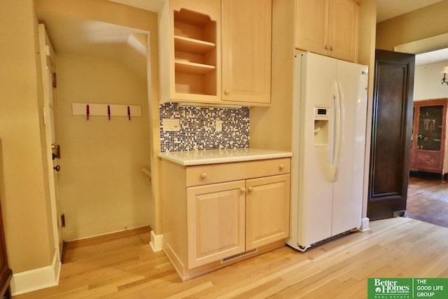 5506 Howard St, Omaha, NE 68106 - kitchen with white fridge with ice dispenser, light wood-type flooring, backsplash, light countertops, and baseboards