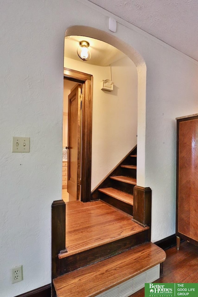 5506 Howard St, Omaha, NE 68106 - stairway featuring arched walkways, wood finished floors, and baseboards