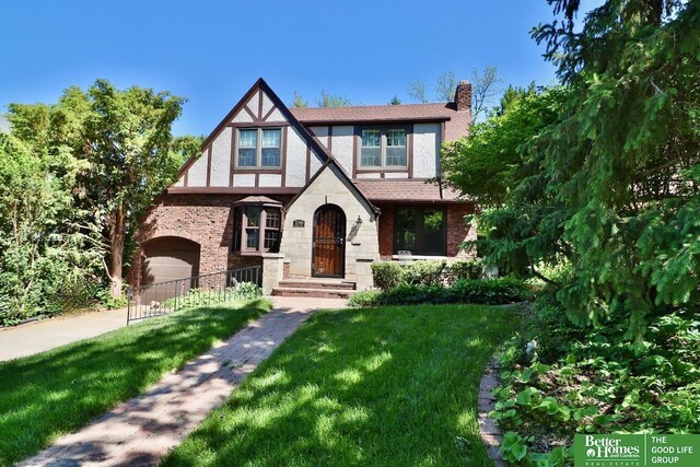 5506 Howard St, Omaha, NE 68106 - tudor home with a chimney, a front yard, brick siding, and a garage