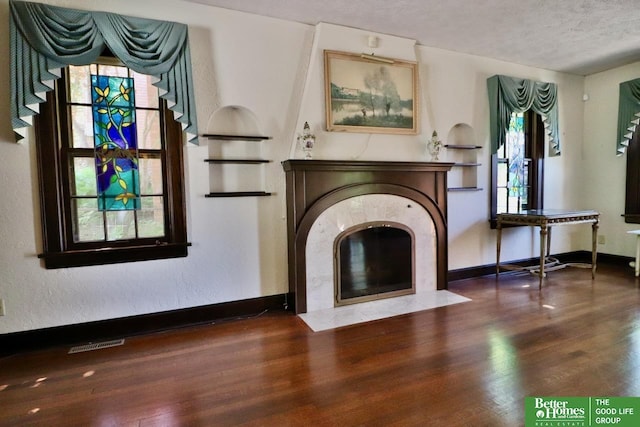 5506 Howard St, Omaha, NE 68106 - unfurnished living room with wood finished floors, a fireplace with flush hearth, a textured ceiling, and baseboards