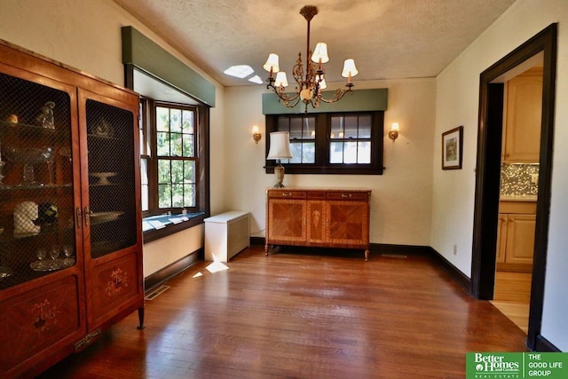 5506 Howard St, Omaha, NE 68106 - dining room featuring dark wood-style flooring, a chandelier, a textured ceiling, and baseboards