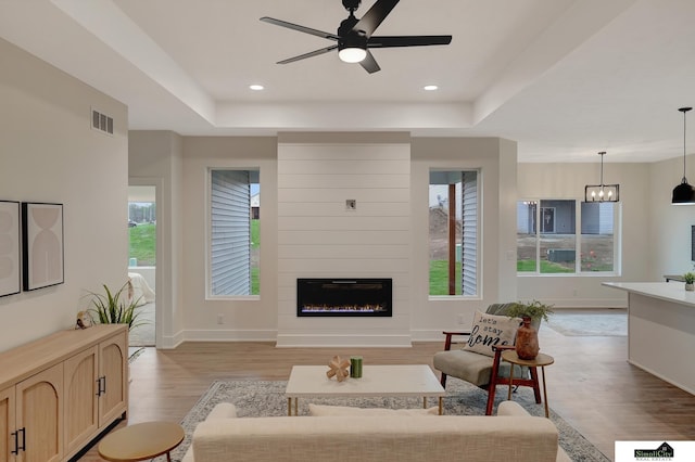living room featuring light wood-type flooring, a ceiling fan, plenty of natural light, and visible vents