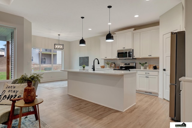 kitchen featuring appliances with stainless steel finishes, a sink, light wood finished floors, light countertops, and tasteful backsplash
