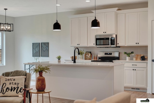kitchen featuring tasteful backsplash, white cabinets, a notable chandelier, stainless steel appliances, and recessed lighting