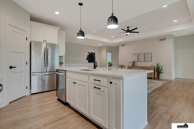 kitchen with a sink, stainless steel appliances, a ceiling fan, light wood-type flooring, and visible vents