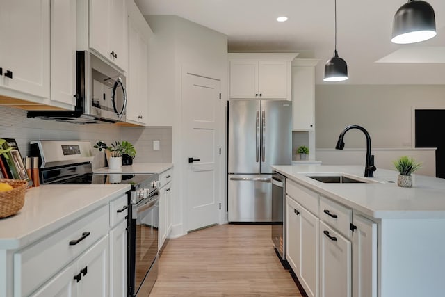 kitchen featuring decorative backsplash, decorative light fixtures, light wood-type flooring, a sink, and stainless steel appliances