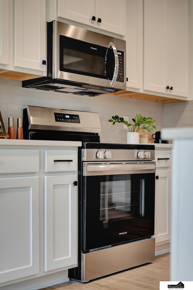 kitchen featuring decorative backsplash, white cabinetry, appliances with stainless steel finishes, and light wood finished floors