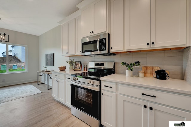 kitchen featuring white cabinets, appliances with stainless steel finishes, light countertops, light wood-type flooring, and backsplash