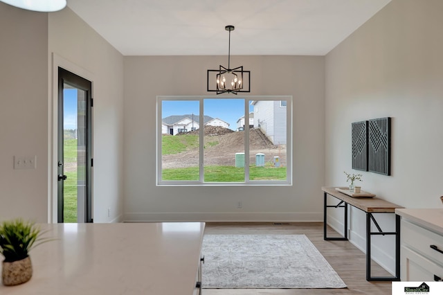 dining space with baseboards, light wood-type flooring, and a notable chandelier