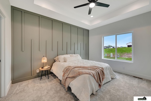bedroom featuring a tray ceiling, baseboards, carpet flooring, and visible vents