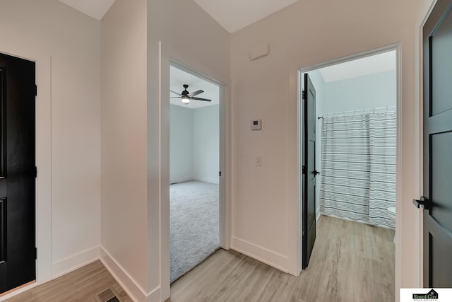 hall with baseboards, visible vents, and light wood-style flooring