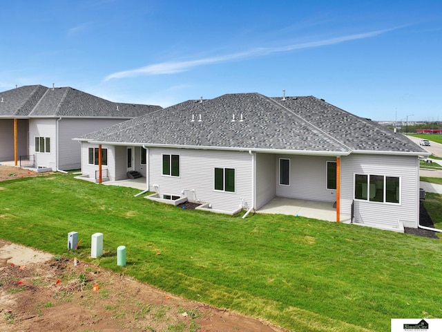 back of house with a yard, a shingled roof, and a patio area