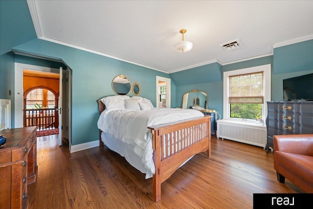 bedroom with wood finished floors, radiator, visible vents, baseboards, and ornamental molding