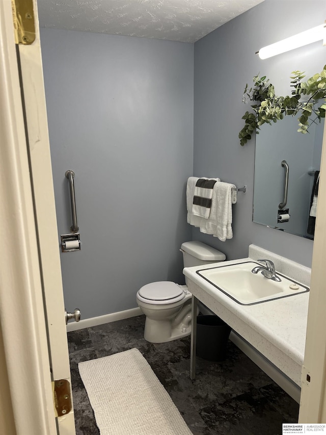 half bathroom featuring toilet, a textured ceiling, and a sink