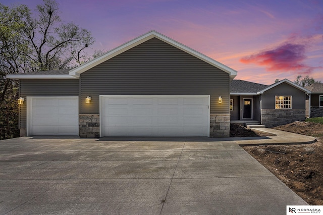 view of front of house with an attached garage, driveway, and stone siding