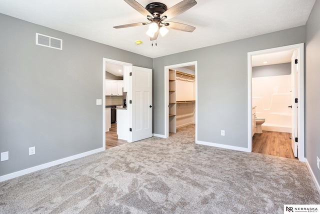 unfurnished bedroom featuring visible vents, carpet, a walk in closet, and baseboards