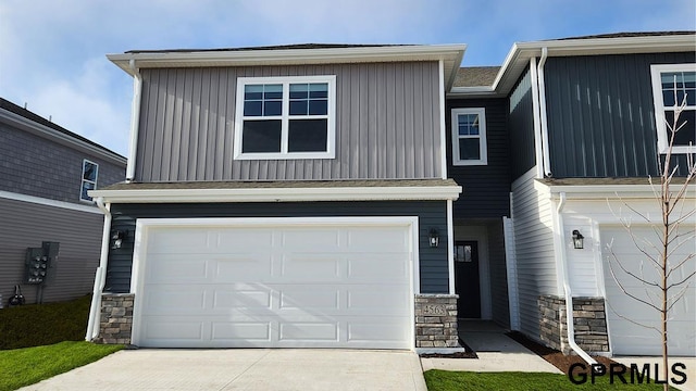 view of front of home with board and batten siding, an attached garage, concrete driveway, and stone siding