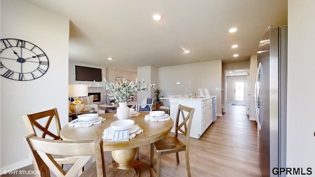 dining area featuring recessed lighting, baseboards, a glass covered fireplace, and light wood-type flooring