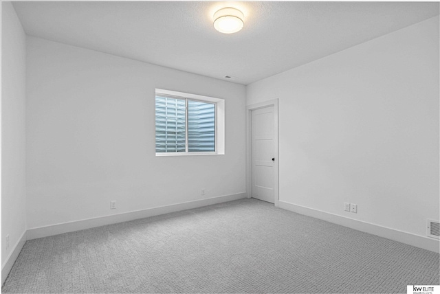 unfurnished room featuring light carpet and baseboards