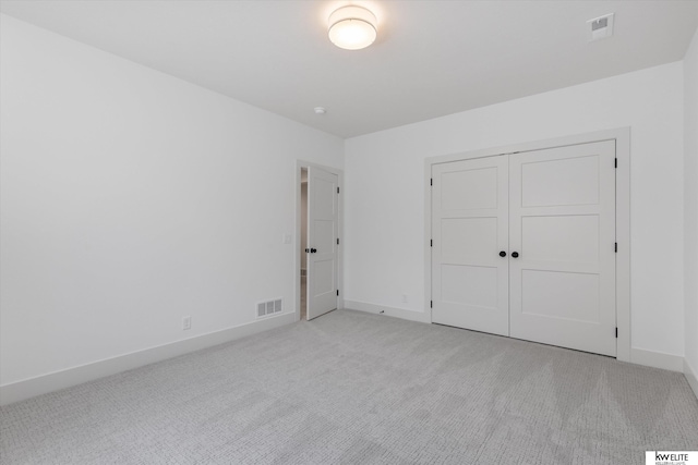 unfurnished bedroom with light carpet, baseboards, and a closet