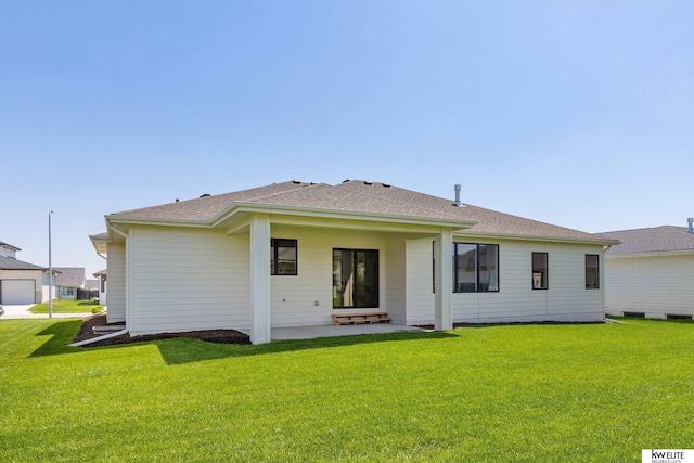 back of property featuring a yard and roof with shingles