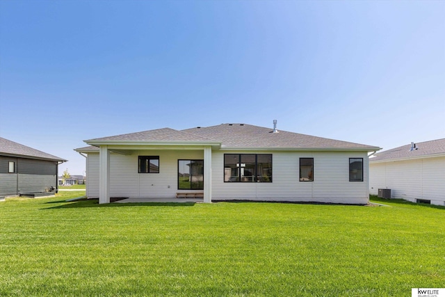 back of property with a lawn, central AC, and a shingled roof