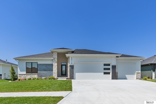 prairie-style house featuring stone siding, an attached garage, concrete driveway, and a front yard