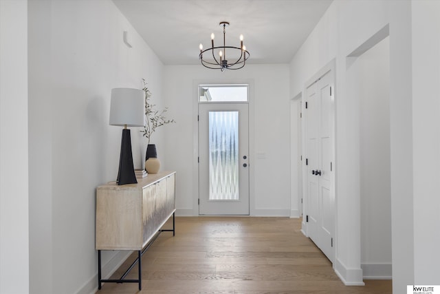 entryway with a chandelier, light wood finished floors, and baseboards