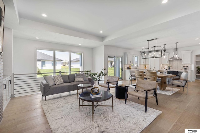 living area with recessed lighting, light wood-style flooring, and a raised ceiling