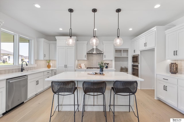 kitchen featuring appliances with stainless steel finishes, white cabinetry, a kitchen island, decorative backsplash, and recessed lighting