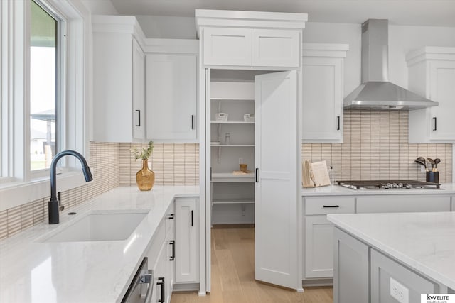 kitchen featuring wall chimney exhaust hood, a sink, stainless steel appliances, and plenty of natural light