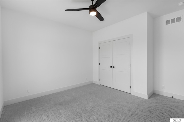 unfurnished bedroom featuring light carpet, a closet, baseboards, and ceiling fan