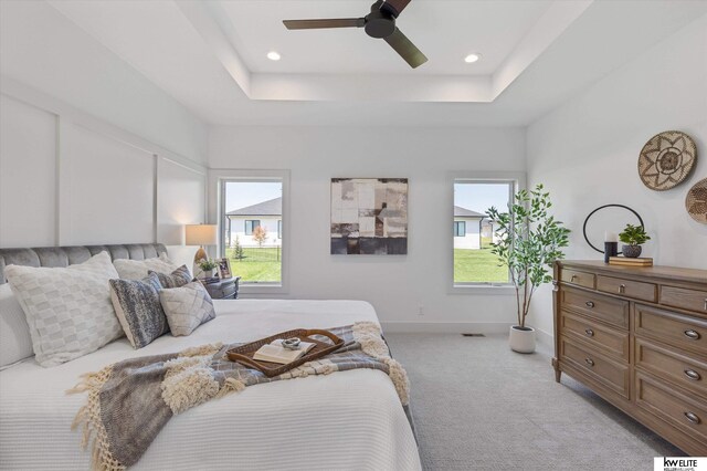 bedroom with light carpet, a ceiling fan, a tray ceiling, baseboards, and recessed lighting